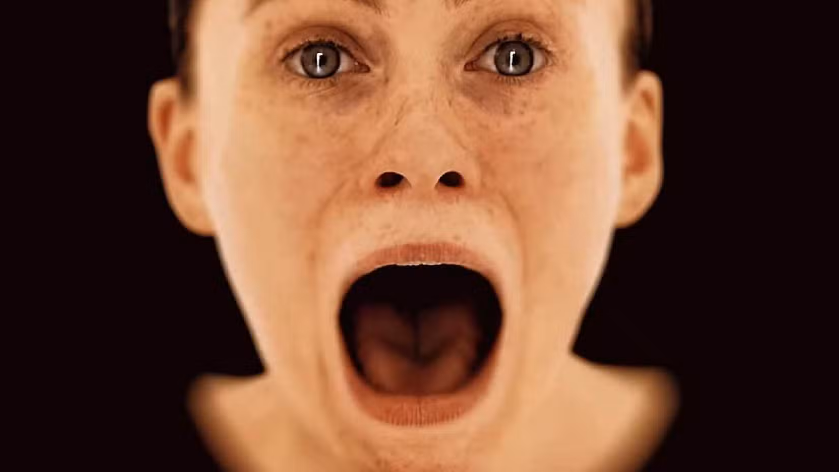 Testa disincarnata di una donna che urla su sfondo marrone, teaser di OD