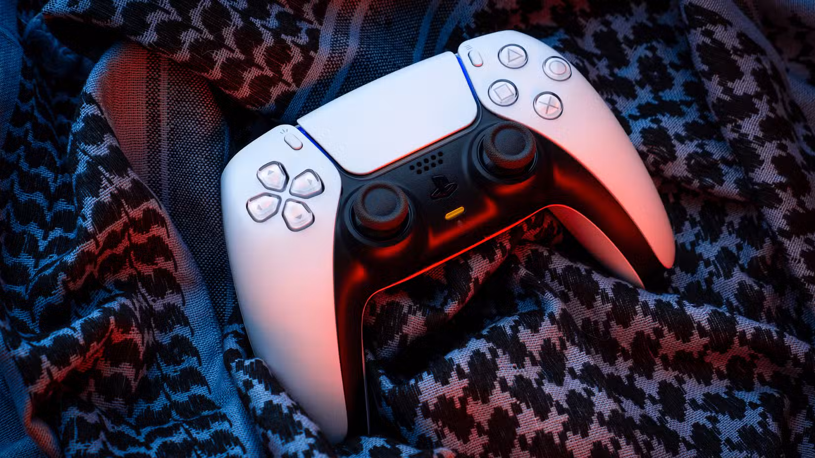 Controller DualSense su tessuto nero, simbolo di PlayStation Plus 2026